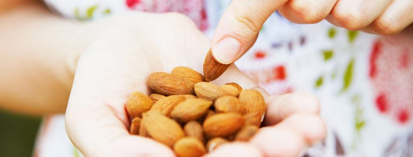 Picture of a woman holding a handful of almonds.