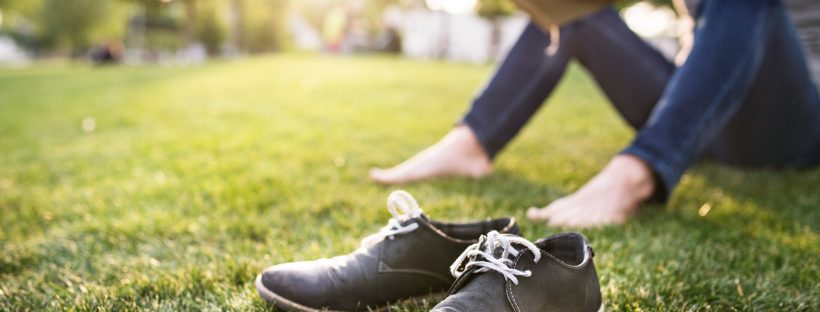 Photo of a person sitting barefoot in a park reading