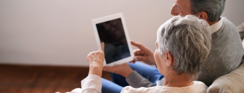 A man and a woman look at an ipad