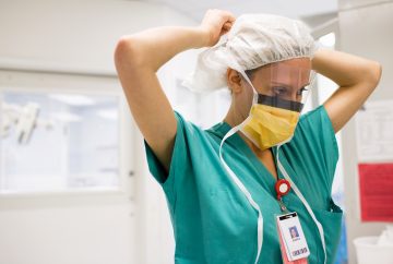 Photo of a nurse tying a face mask around her head.
