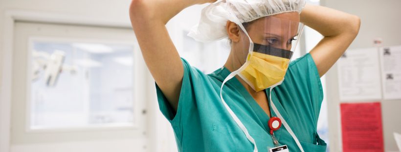 Photo of a nurse tying a face mask around her head.