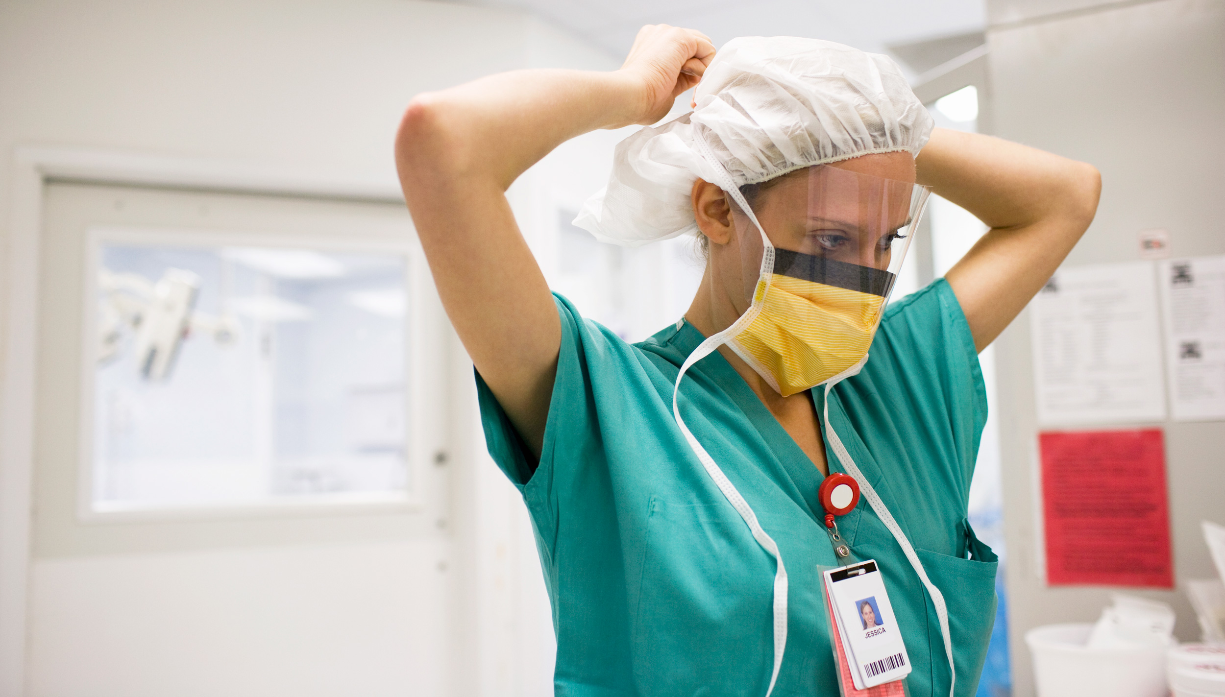 Photo of a nurse tying a face mask around her head.