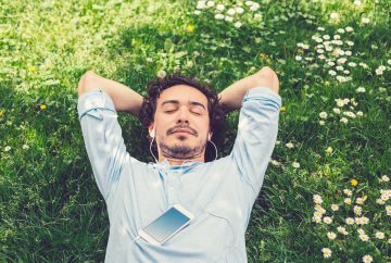 Picture of a man lying in the grass listening to music