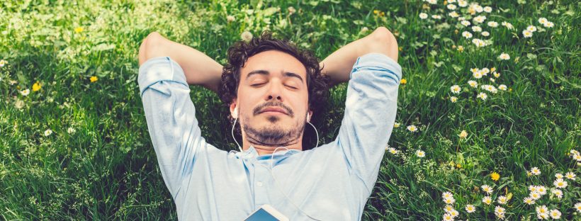 Picture of a man lying in the grass listening to music