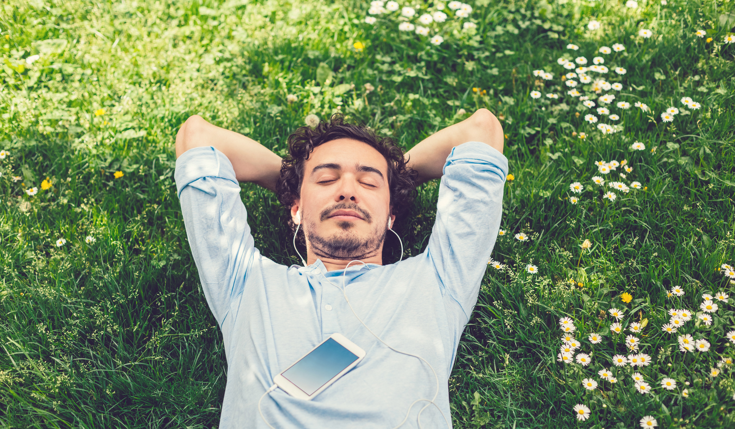 Picture of a man lying in the grass listening to music