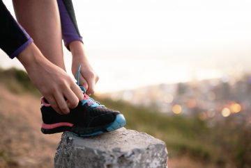 Picture of a person's shoe being tied on a rock.