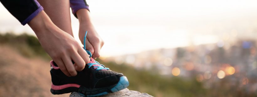 Picture of a person's shoe being tied on a rock.