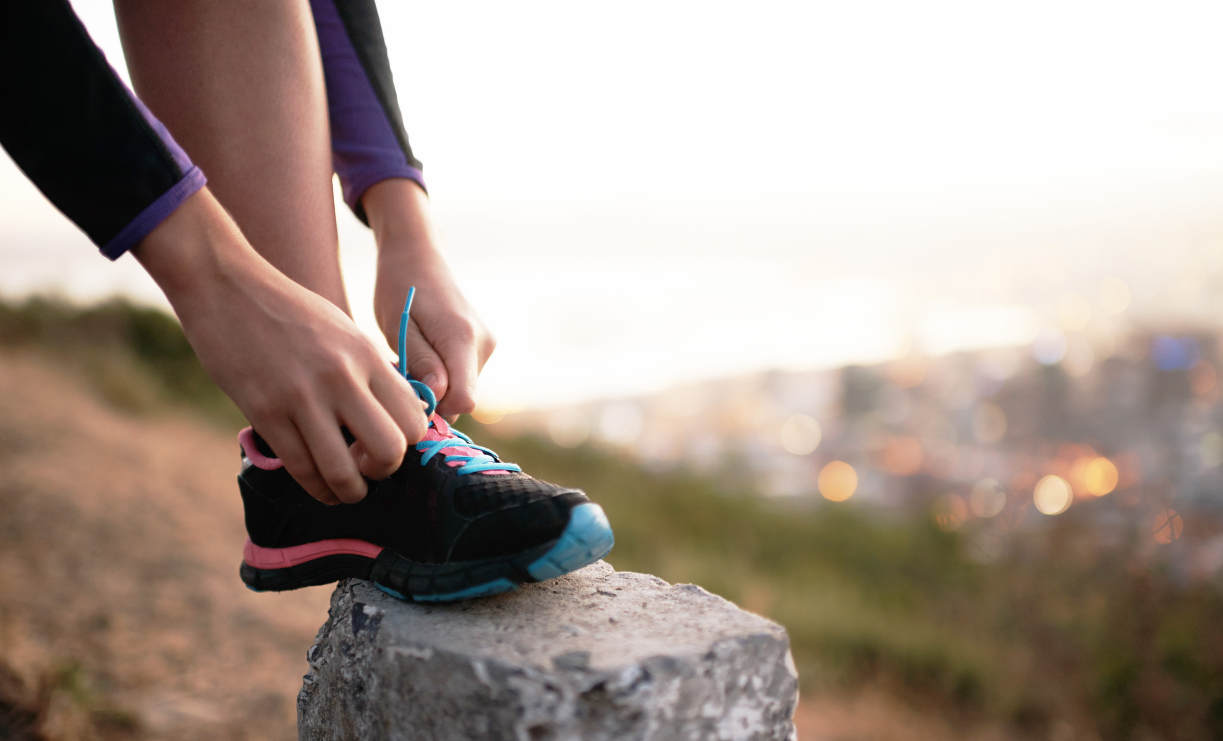 Picture of a person's shoe being tied on a rock.