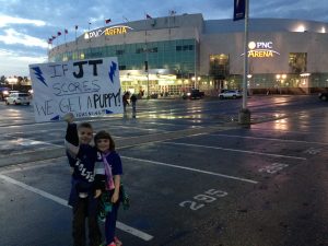 Two kids holding a sign standing in front of a hockey arena.