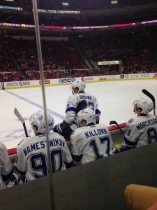 Picture of hockey players on bench and one getting out of the bench.