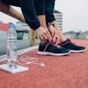 Picture of a woman lacing up her sneakers on a track