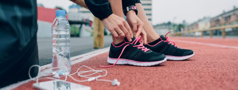 Picture of a woman lacing up her sneakers on a track
