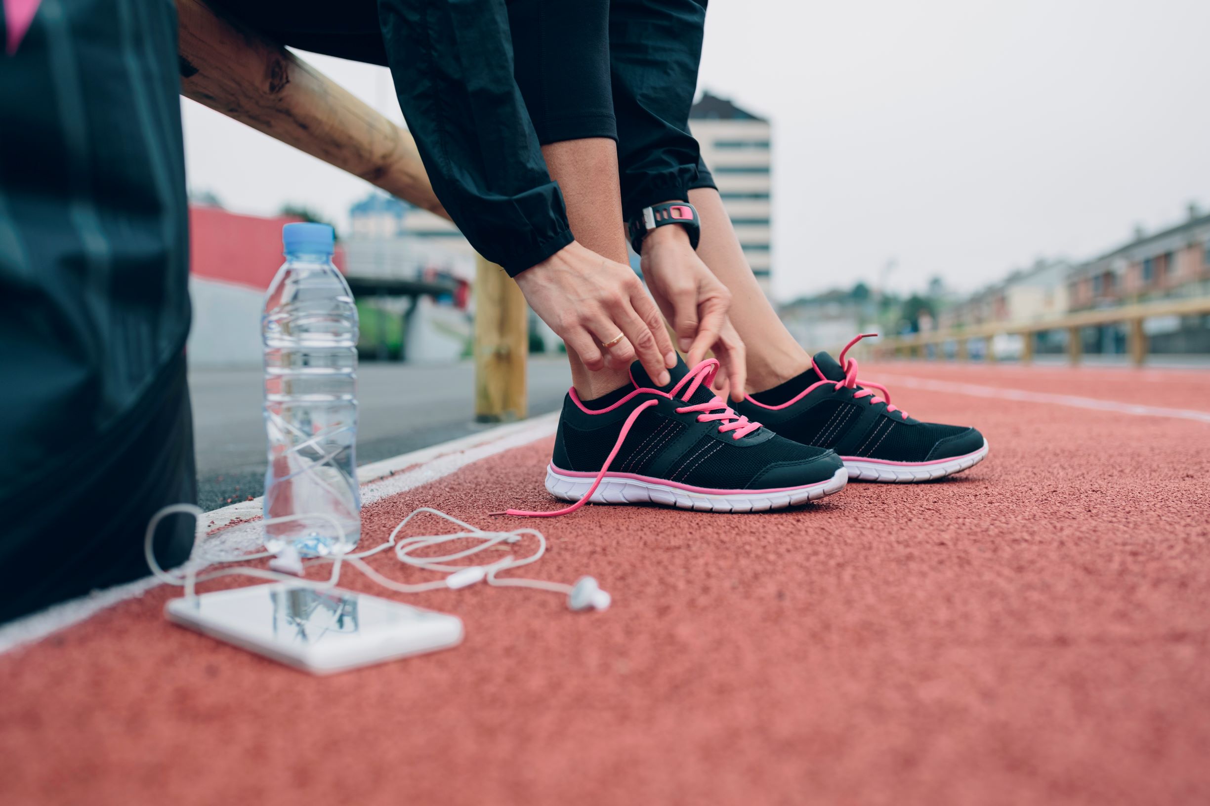 Picture of a woman lacing up her sneakers on a track