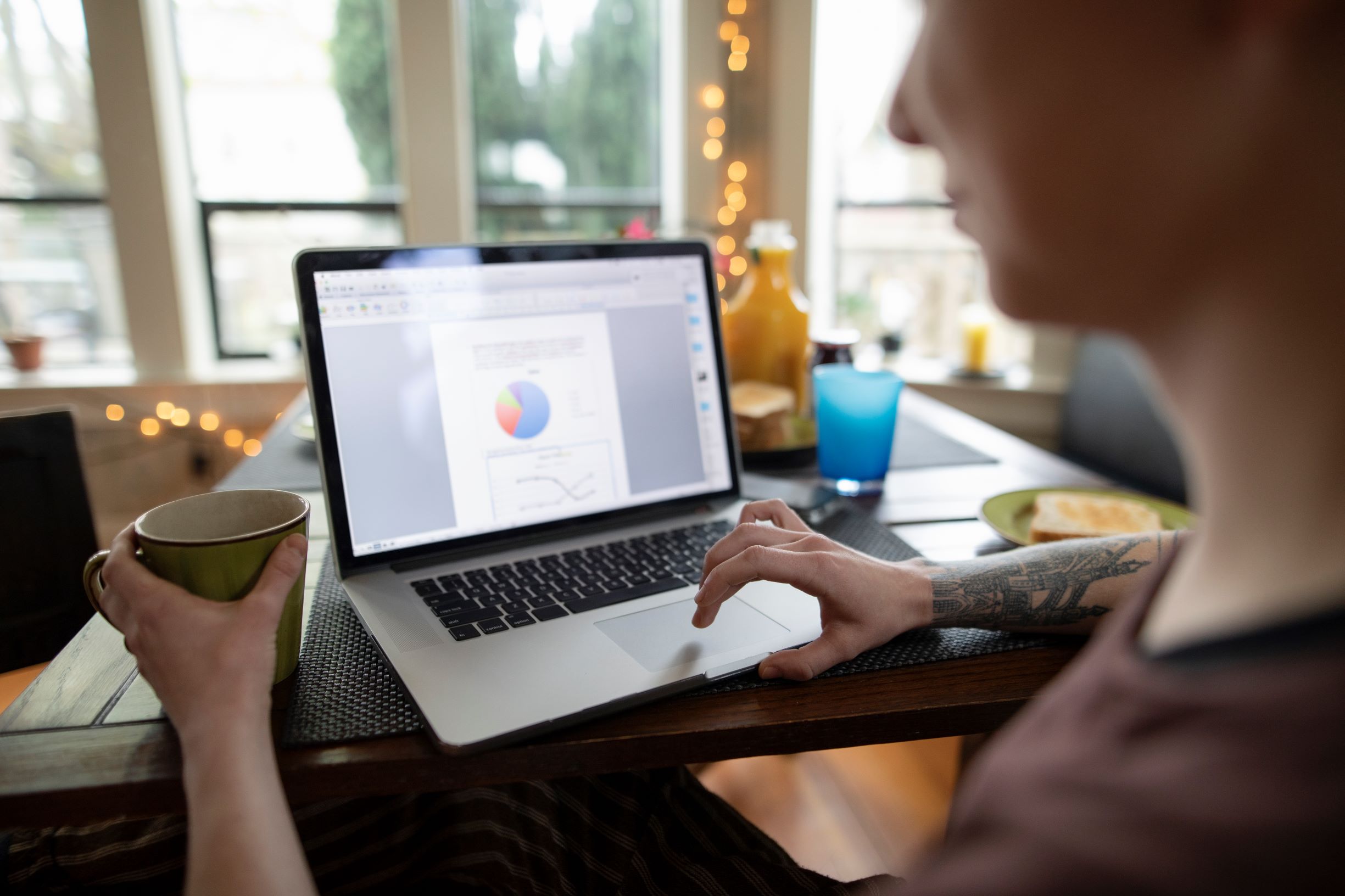 Picture of a person sitting at a kitchen table working at a laptop.