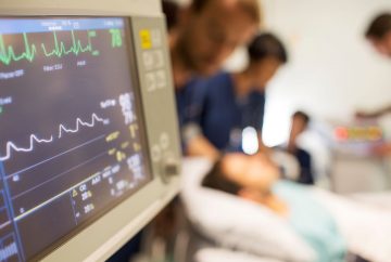 Picture of someone in a hospital bed with medical professionals around them