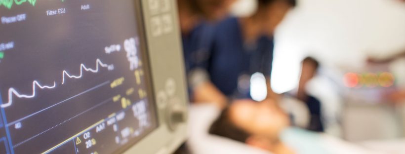 Picture of someone in a hospital bed with medical professionals around them