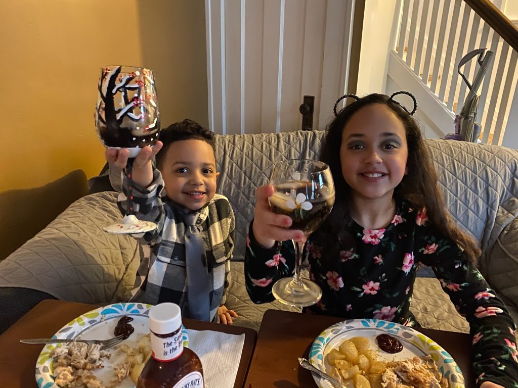 Picture of two children raising a glass to cheers over dinner