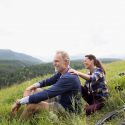 Man and woman sitting on a hill by valley