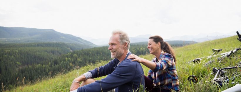 Man and woman sitting on a hill by valley