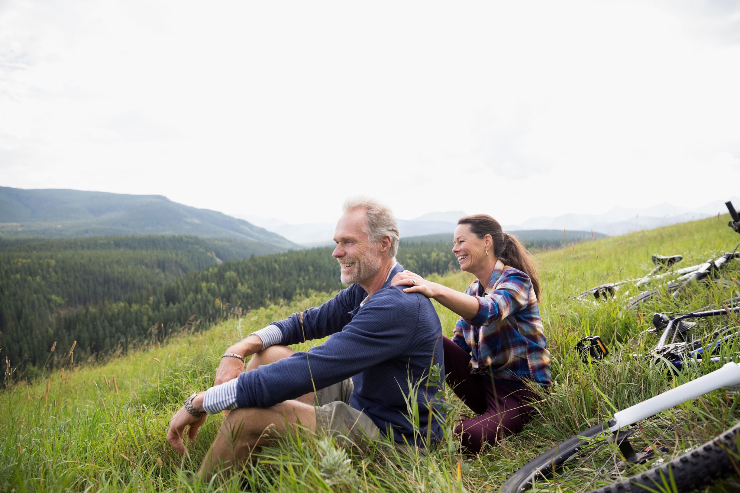 Man and woman sitting on a hill by valley