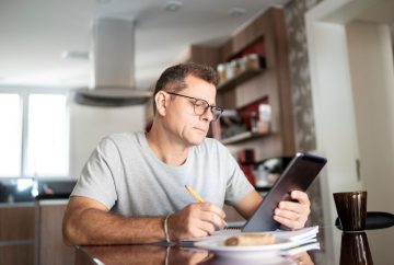 Picture of a man sitting at a table with an ipad