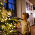 picture of a boy standing next to a christmas tree