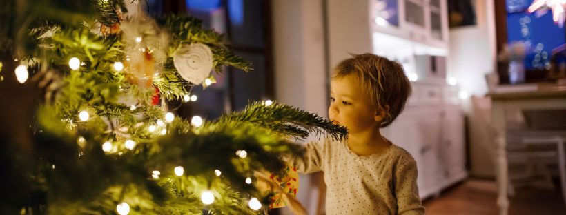 picture of a boy standing next to a christmas tree